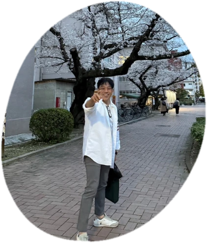 桜並木の道で、こちらに手を伸ばして笑う石井さん