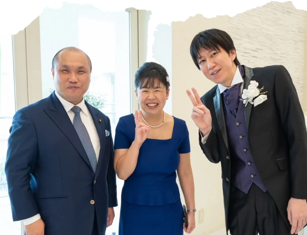 結婚式場で、来賓の男性・新郎とピースサインをする石浜さん